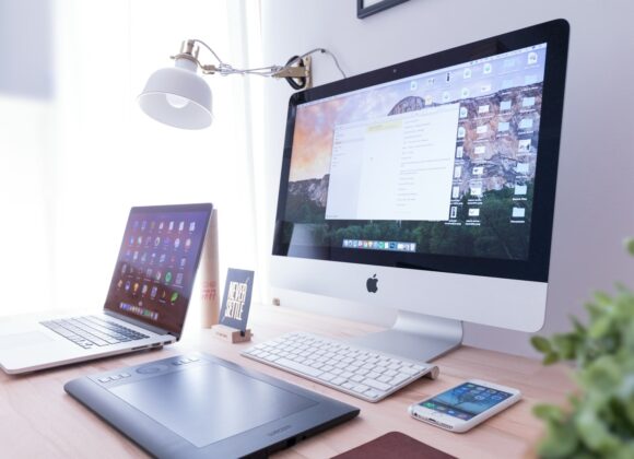 silver iMac near iPhone on brown wooden table
