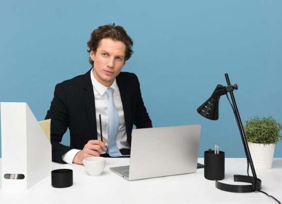 man sitting on chair beside laptop computer and teacup
